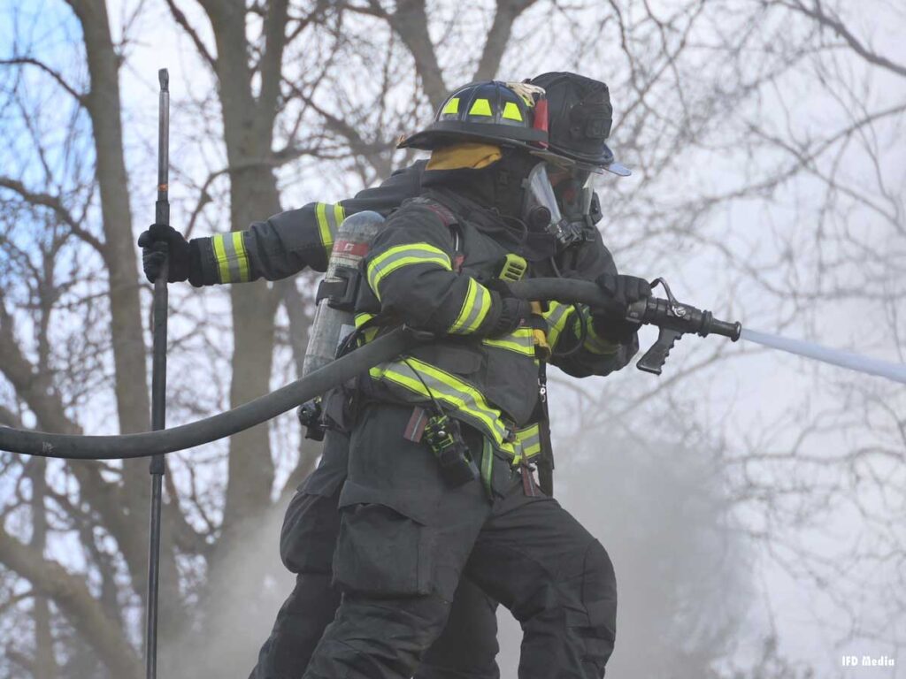 Firefighters on a roof with a hoseline