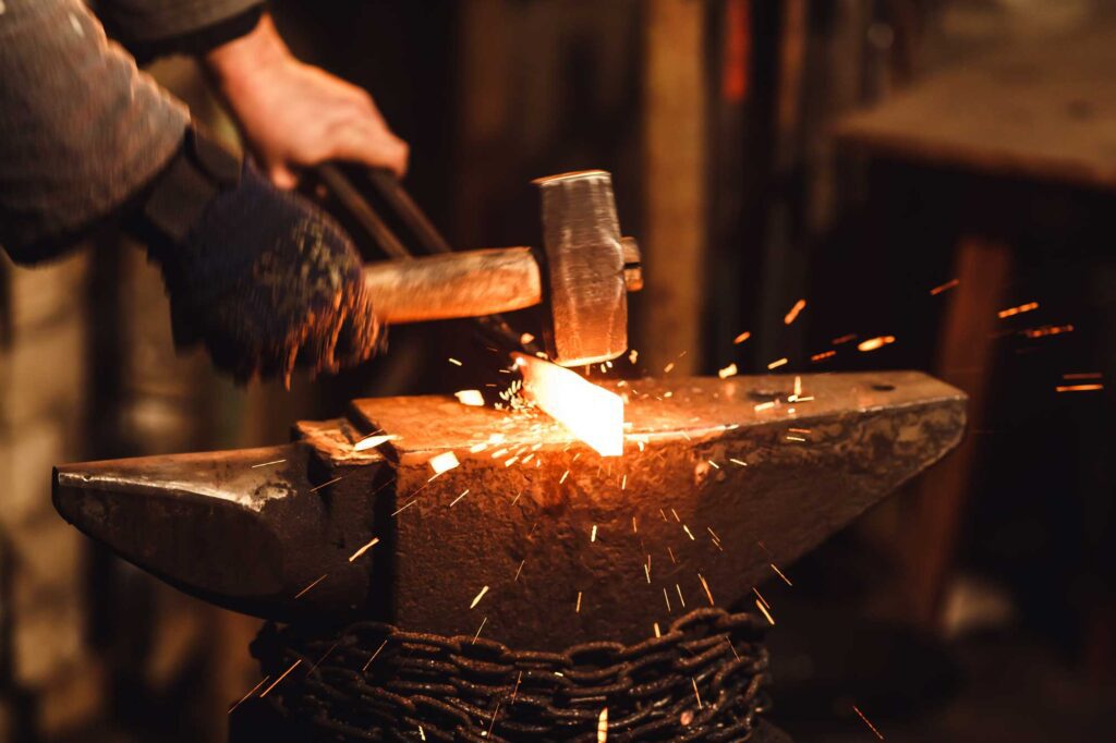 Blacksmith working metal with hammer